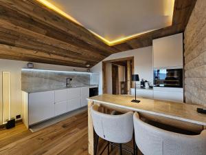 a kitchen with wooden ceilings and a stone wall at Magnifique attique avec vue sur le lac de la Moubra in Crans-Montana