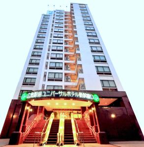 ein hohes weißes Gebäude mit einer Treppe davor in der Unterkunft Hiroshima Ekimae Universal Hotel in Hiroshima