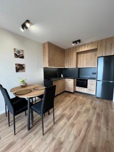 uma cozinha com uma mesa e cadeiras e um frigorífico em Apartament Broniewskiego em Busko-Zdrój