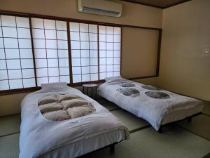 twee bedden in een kamer met grote ramen bij 大和屋ホテルいろは in Nikko