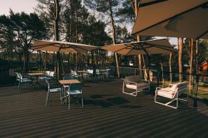 une terrasse avec des tables, des chaises et des parasols dans l'établissement Folga Resort, à Mrzeżyno