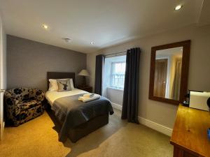 una camera con letto, sedia e specchio di The Golden Fleece Inn a Porthmadog