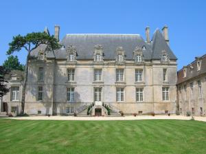 a large castle with a grass field in front of it at Chateau de Courseulles in Courseulles-sur-Mer