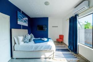 een blauwe slaapkamer met een bed en een rode stoel bij The Crescent Victoria Falls in Victoria Falls