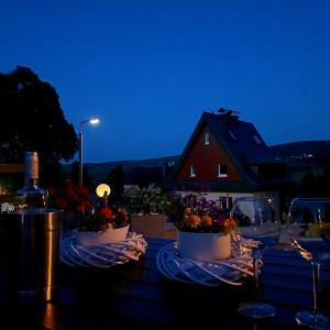 una mesa con flores y copas de vino por la noche en Apartments - Lehmanns Ferienwohnungen, en Kurort Oberwiesenthal