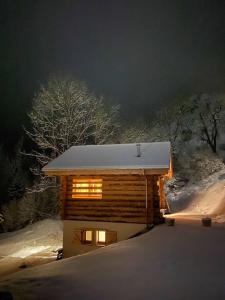 une cabane en rondins dans la neige la nuit dans l'établissement 1000 Borne Caffe Hebergements Insolites, à Entremont