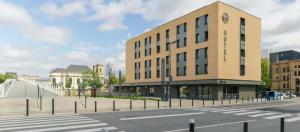 a building with a clock on the side of a street at B&B HOTEL Thionville Centre Gare Porte du Luxembourg A31 in Thionville