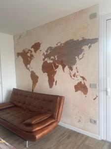 um sofá de couro num quarto com um mapa do mundo na parede em Attico Sole em Lido di Jesolo