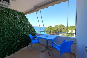 d'une table bleue et de chaises sur un balcon avec vue sur l'océan. dans l'établissement Livia's Guesthouse, à Ksamil