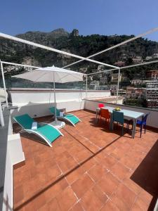 eine Terrasse mit einem Tisch, Stühlen und einem Sonnenschirm in der Unterkunft Casa Positano in Positano