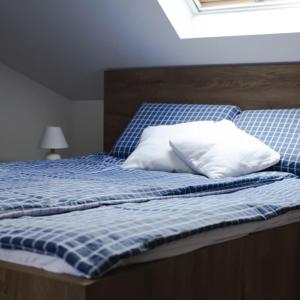 a bed with blue and white sheets and pillows at Győri vendégház in Demjén