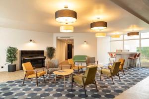 een lobby met stoelen en tafels en een open haard bij Le Carline, Sure Hotel Collection by Best Western in Caen