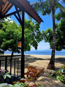 einen Strand mit einer Bank, Palmen und dem Meer in der Unterkunft Beach House Penida in Nusa Penida