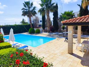 una piscina en un patio con palmeras en Sunset Green 02, en Pafos