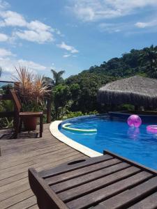 a swimming pool with a wooden deck with a chair at Pousada Éden in Angra dos Reis