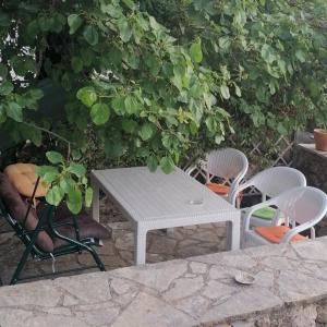 een witte picknicktafel en stoelen onder een boom bij MELPO in Évyiros