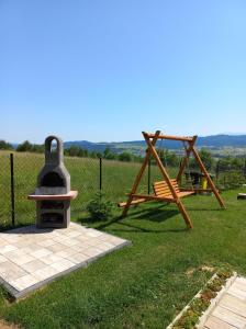 une aire de jeux avec un grill et une balançoire dans l'établissement Domek na Hubce II, à Maniowy