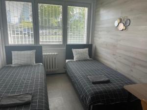 a bedroom with two beds and two windows at Warszawa Zachodnia in Warsaw