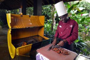 Un homme dans un chapeau cuisinant des plats sur un grill dans l'établissement Sunset at the Palms Resort - Adults Only - All Inclusive, à Negril