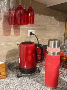 a red coffee pot on a counter next to a thermos at La Choza VIP Roja in Coquimbo