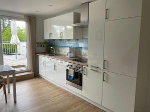 cocina con armarios blancos, mesa y ventana en City Wohnung mit Gartenblick und Dachterrasse, en Verden