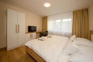 a bedroom with a white bed and a television at Apartmán nad Ottovkou in Luhačovice