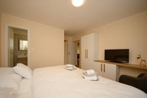 a bedroom with a white bed and a television at Apartmán nad Ottovkou in Luhačovice