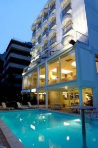 a large building with a swimming pool in front of a building at Hotel Royal Plaza in Rimini