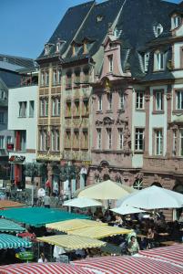 um grupo de mesas com guarda-chuvas em frente aos edifícios em Ferienwohnung "Schön Wohnen in Mainz" em Mainz