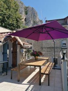 um guarda-chuva roxo sobre uma mesa de piquenique no pátio em Maison Bossanne em Barbières