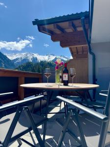 - une table avec deux verres de vin et des fleurs sur le balcon dans l'établissement Apartment Waldherz, à Wald im Pinzgau