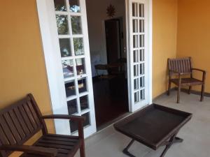 two chairs and a bench in a room with a door at Pousada Éden in Angra dos Reis