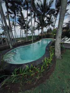 una piscina en un patio con palmeras en Uma Pantai Seseh, en Canggu