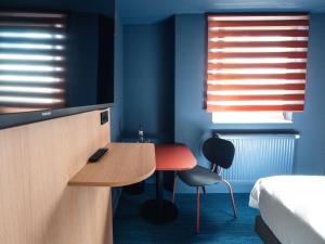 um quarto com uma mesa e duas cadeiras e uma cama em Ibis Styles Charleroi Airport Aero 44 em Charleroi