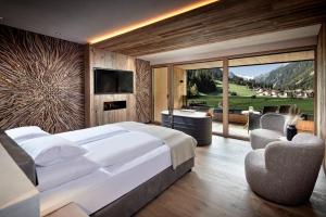 um quarto com uma grande cama branca e uma televisão em Living & Spa Vitalhotel Edelweiss em Neustift im Stubaital