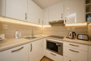 a kitchen with white cabinets and a sink and a microwave at Apartmán nad Ottovkou in Luhačovice