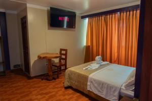 Cette chambre comprend un lit, une table et une télévision. dans l'établissement Hotel California, à Chachapoyas