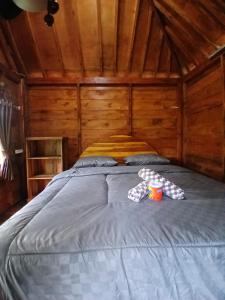 a large bed in a wooden cabin with two cups on it at MY HOME tetebatu in Tetebatu