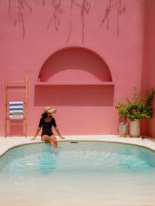 une femme dans un chapeau assise dans une piscine dans l'établissement VA Villa Jimbaran Bali, à Jimbaran