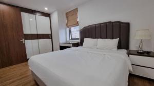 um quarto com uma grande cama branca e uma cabeceira em madeira em Phong Lan Apartments em Hai Phong