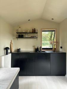 una cocina con armarios negros y una ventana en Tiny House mit Garten in der Lüneburger Heide, en Soltau