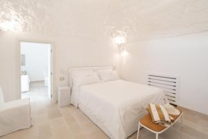 a white bedroom with a white bed and a chair at Borgofreddo Luxury Suite in Monopoli