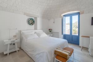 a white bedroom with a bed and a blue door at Borgofreddo Luxury Suite in Monopoli