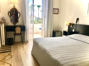 een slaapkamer met een bed, een bureau en een raam bij Hotel des Mimosas in Juan-les-Pins