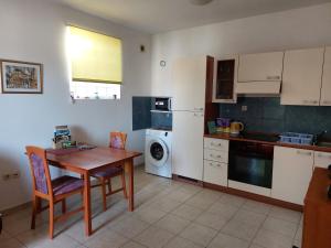 cocina con mesa de madera y cocina con lavadora en Latmo Apartment Zadar, en Zadar