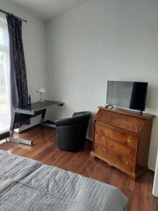 ein Schlafzimmer mit einem Schreibtisch und einer Kommode mit einem TV darauf in der Unterkunft Wohnung EG Gotha in Gotha