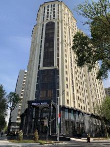 een hoog wit gebouw in een stadsstraat bij Hotel Panorama in Doesjanbe