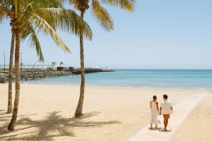 een paar op een strand met palmbomen bij Arrecife Gran Hotel & Spa in Arrecife