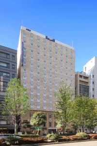 um edifício alto com um sinal em cima em Keio Presso Inn Ikebukuro em Tóquio