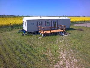 un mobile home dans un champ de fleurs jaunes dans l'établissement Ranczo Tomaszówka Domek w Polu, 